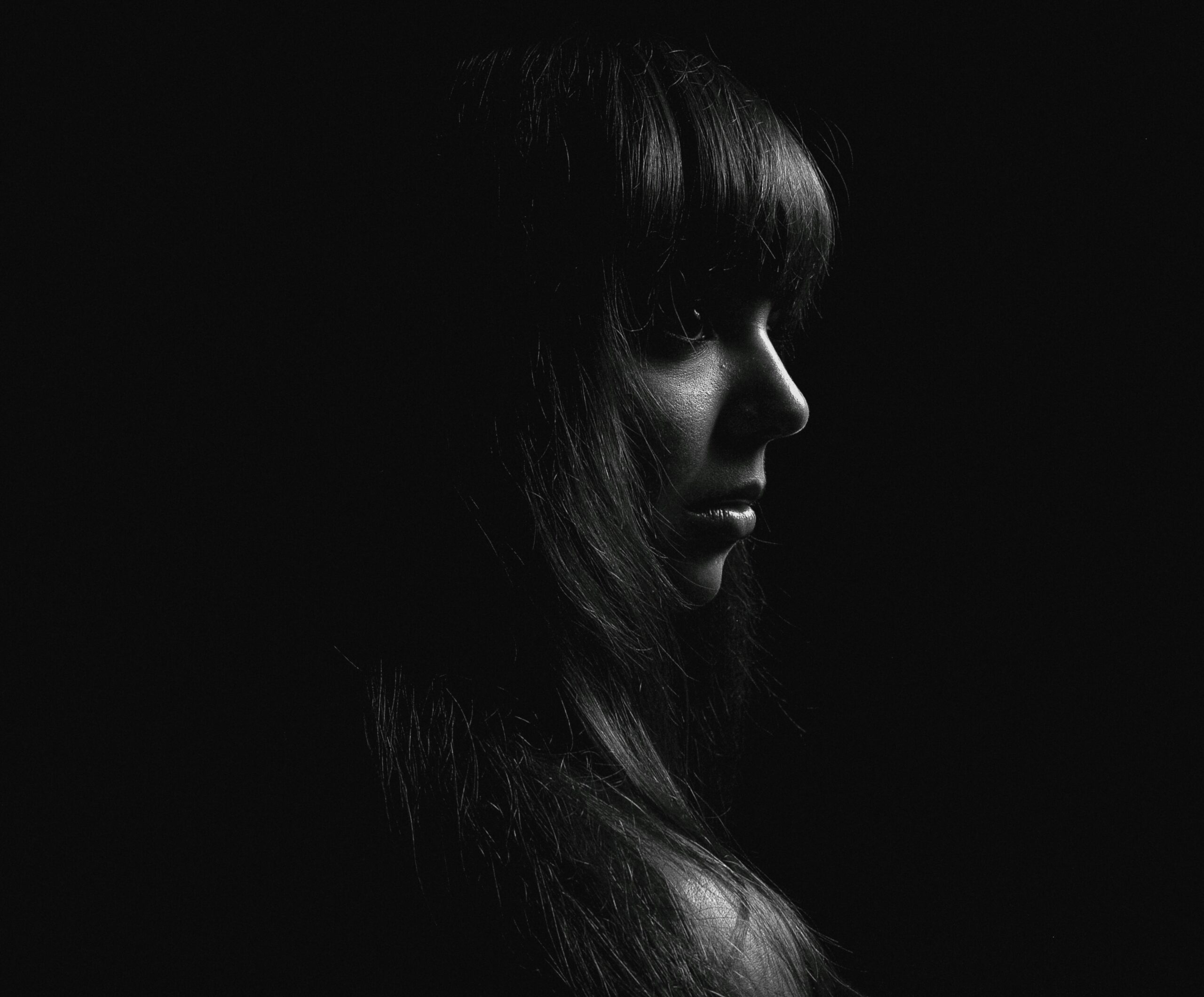 Artistic black and white profile portrait of a woman with long hair, dramatic lighting.